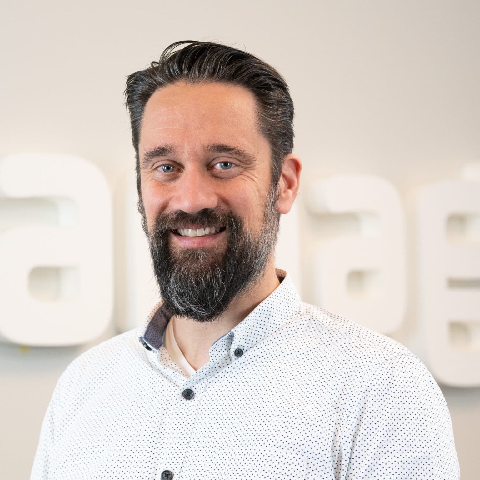 Mann mit Bart und Hemd vor Urban Places Academy Logo.